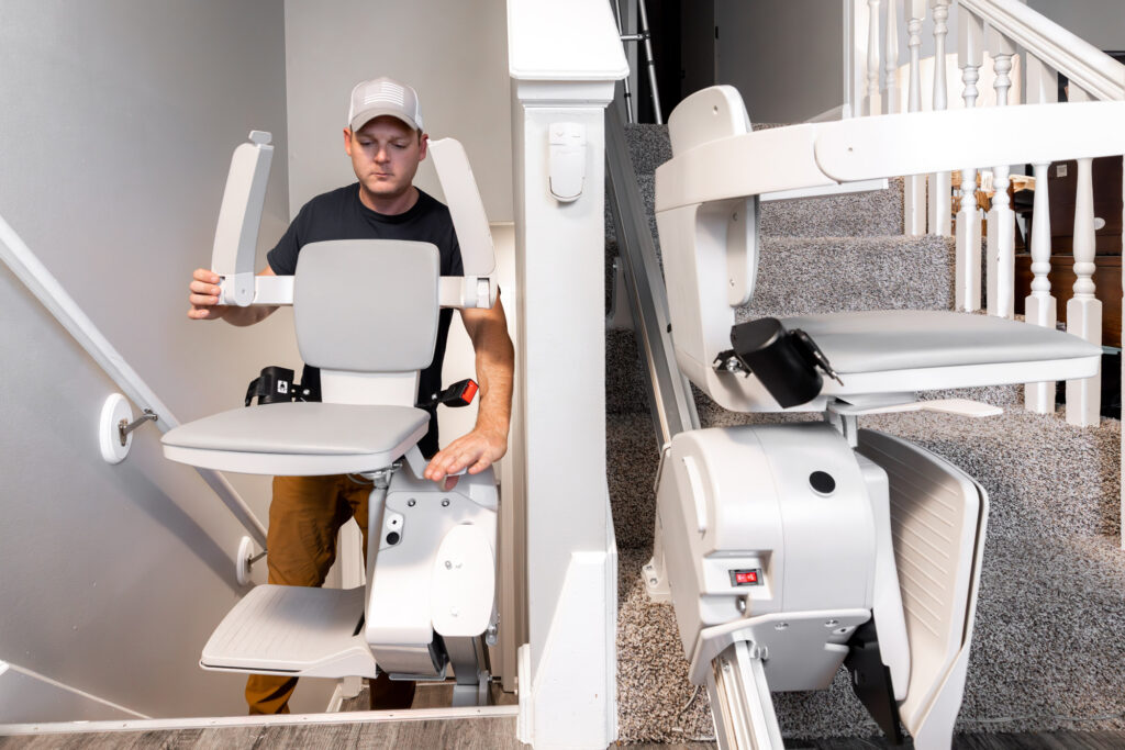 man repairs stair lift on stairway