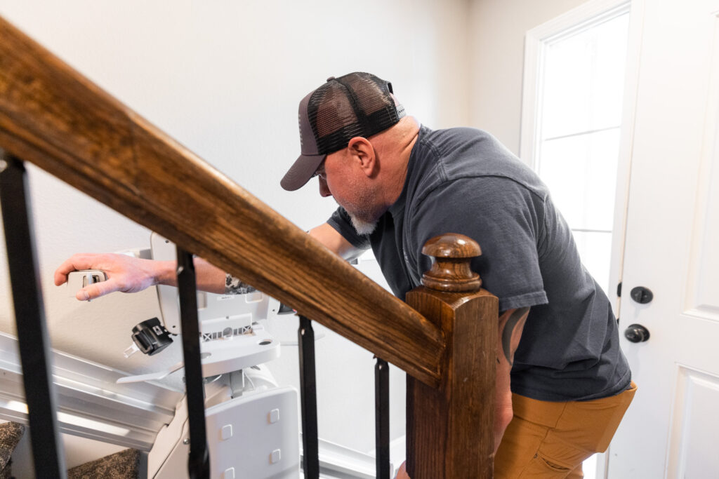 man installs stair lift on narrow staircase